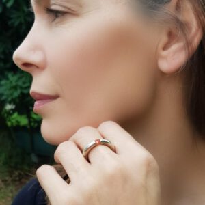 טבעת העשויה מצינור כסף עגול ועבה עם זירקון כתום בוהק במרכזה.