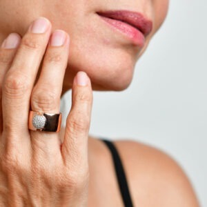 טבעת כסף רחבה בציפוי זהב אדום עם עיגול משובץ זירקונים במרכזה.